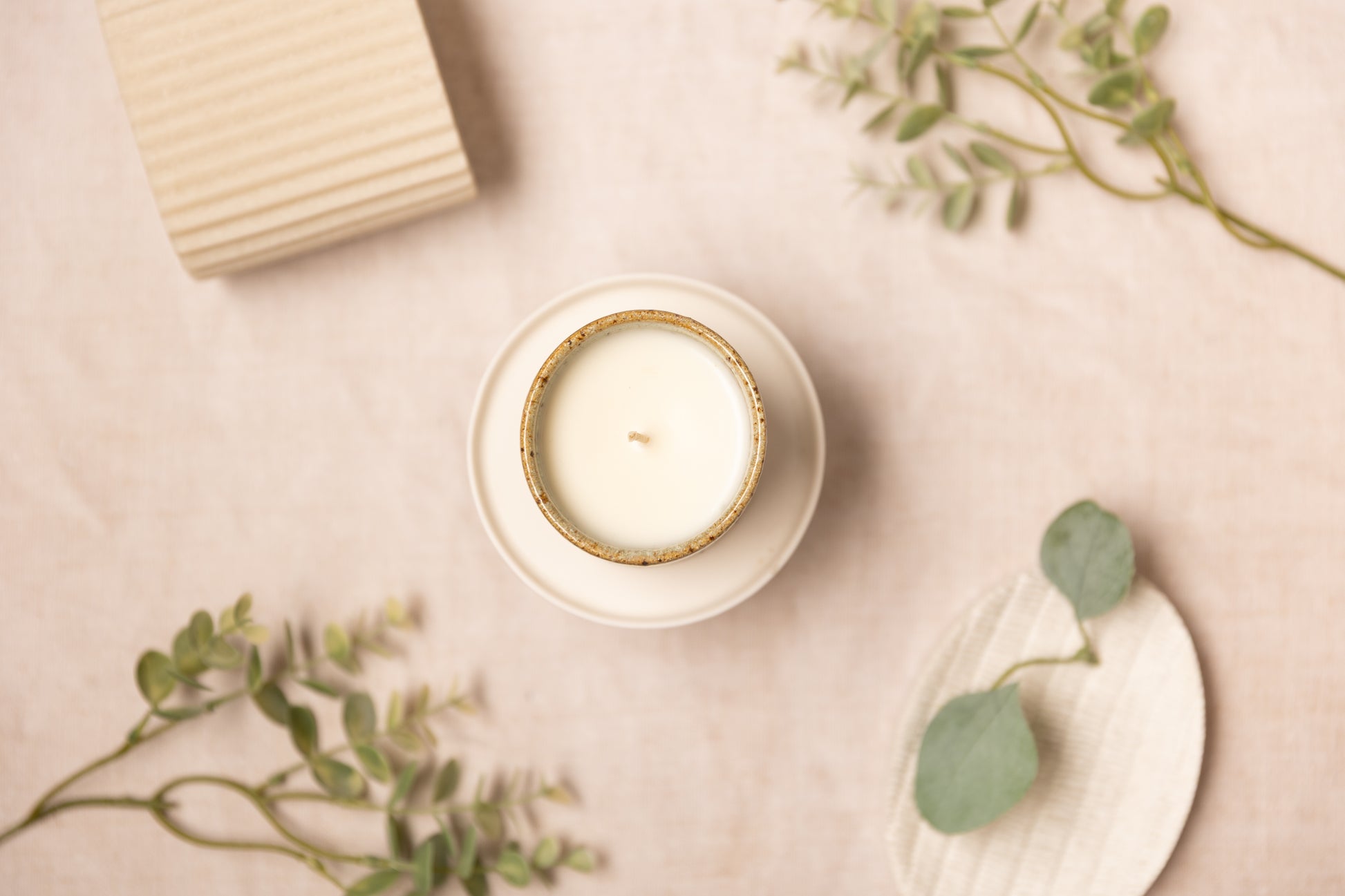 aromatherapy candle with a ceramic handmade pot on a beige fabric background