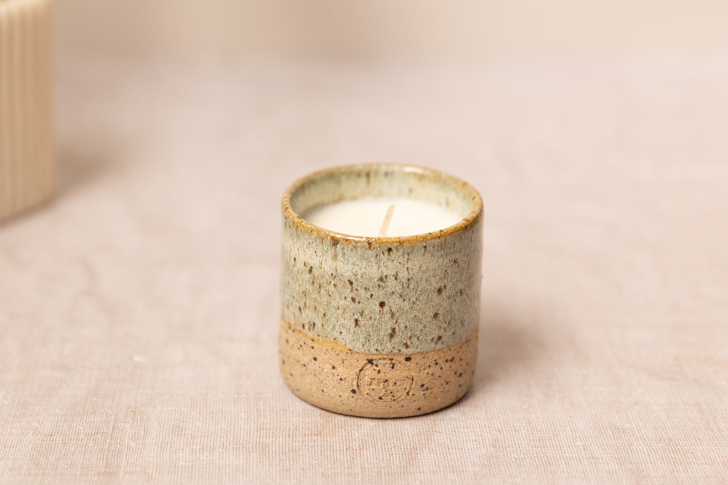 aromatherapy candle with a ceramic handmade pot on a beige fabric background